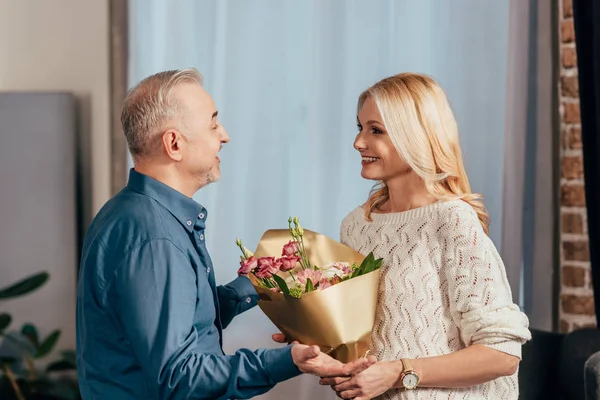 Lycklig Man Ler Samtidigt Blommor Till Attraktiva Hustru Hemma — Stockfoto
