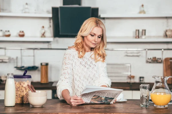 Ελκυστική Ξανθιά Γυναίκα Διαβάζει Εφημερίδα Στην Κουζίνα — Φωτογραφία Αρχείου