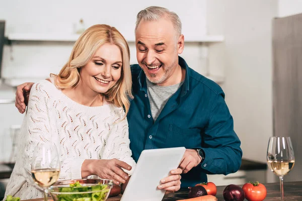 デジタル タブレットの台所で見て陽気なカップルの選択と集中 — ストック写真