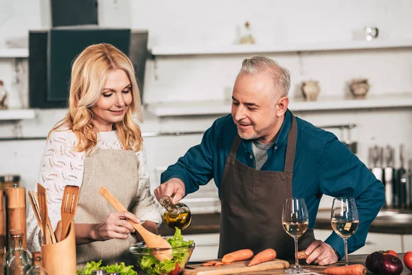 Handsome Husband Pouring Olive Oil Bowl Salad Smiling Wife Kitchen — Stock Photo, Image