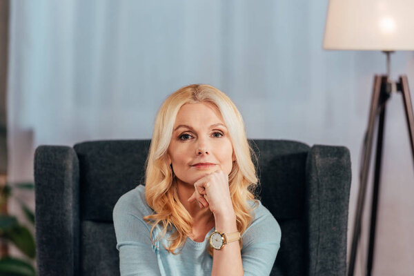 pensive blonde woman looking at camera at home 
