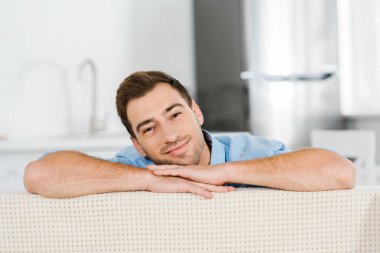 yakışıklı adam kameraya bakıyor ve üzerinde yüz eğilerek gülümseyen evde eller 