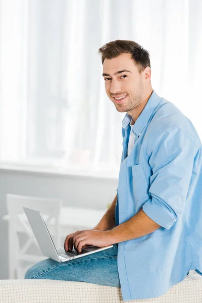 Hombre Sonriente Guapo Sentado Mirando Cámara Utilizando Ordenador Portátil Casa — Foto de Stock