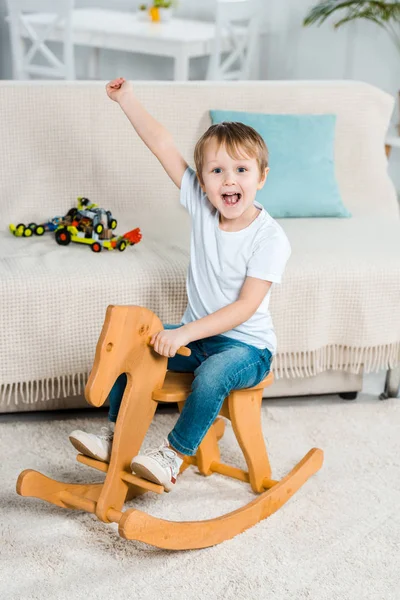 Adorable Excited Preschooler Boy Riding Rocking Horse Gesturing Hand Home — Stock Photo, Image