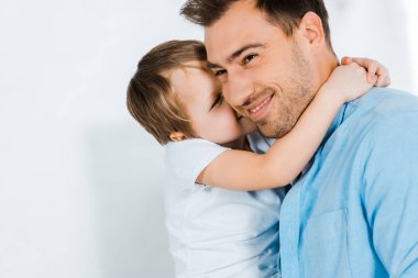 smiling father hugging adorable preschooler son at home with copy space