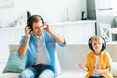 sevimli okul öncesi oğlu evde müzik dinlerken kulaklık ile gülümseyen baba 