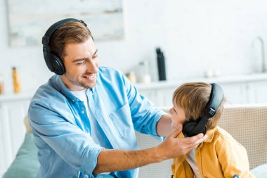 okul öncesi oğlu evde müzik dinlerken kulaklık ile yakışıklı gülümseyen baba 