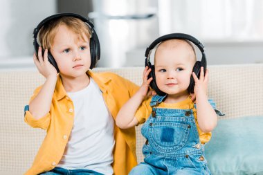 adorable brothers listening music in headphones at home clipart