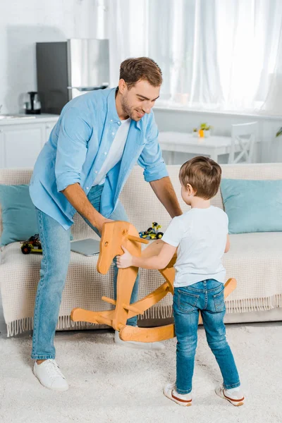 Bonito Pai Filho Pré Escolar Segurando Cavalo Balanço Madeira Casa — Fotografia de Stock