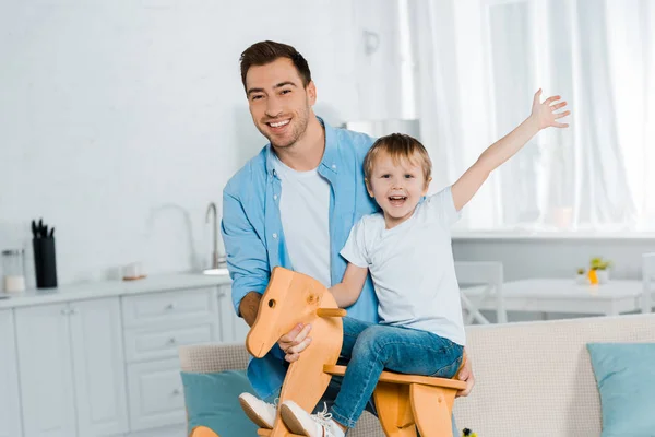 Feliz Padre Mirando Cámara Mientras Emocionado Hijo Preescolar Caballo Mecedora — Foto de Stock