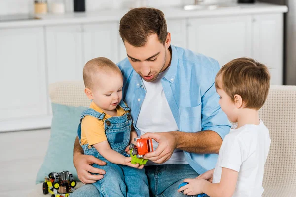 Schöner Vater Sitzt Auf Der Couch Während Süße Vorschulkinder Und — Stockfoto