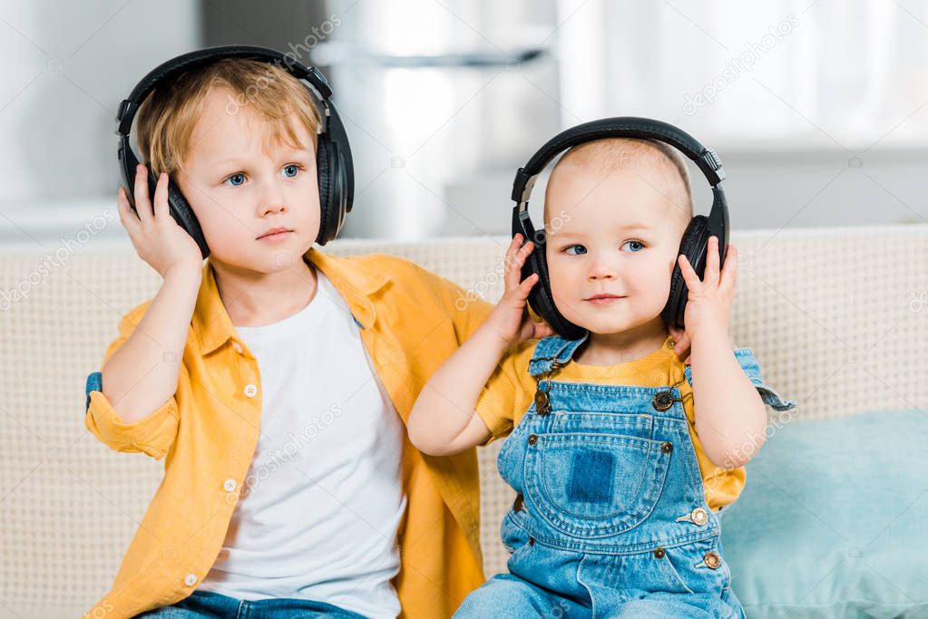 adorable brothers listening music in headphones at home