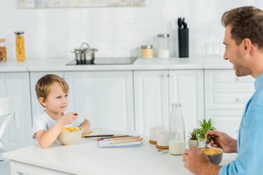 Mısır gevreği mutfakta kahvaltı sırasında baba ve preschooler oğlu