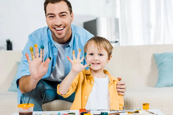 Щасливий Батько Син Дивиться Камеру Показує Пофарбовані Руки Вдома — стокове фото