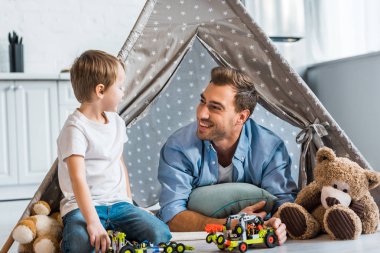oyuncak araba ve oyuncak ayılar Kızılderili çadırı evde altında oynamaya gülümseyen baba ve preschooler oğlu