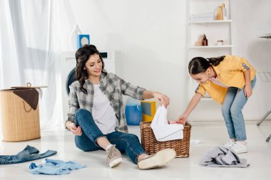 Sarı gömlek ve çamaşır odasında sepetindeki kıyafetler ve havlu koyarak anne kızı