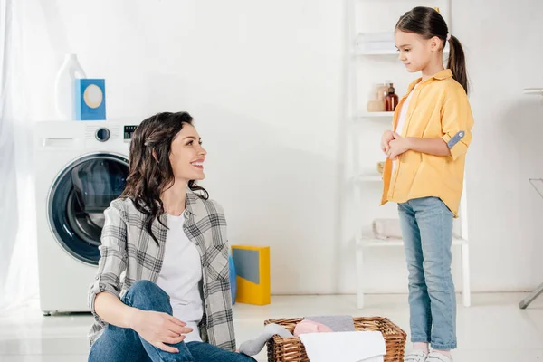 Mother Sitting Floor Basket Looking Daughter Yellow Shirt Smiling Laundry — Stock Photo, Image