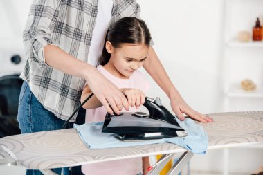 mother and daughter ironing in laundry room clipart