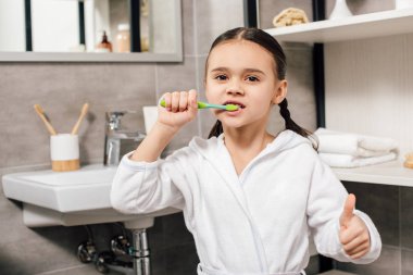 çocuk diş fırçalama ve banyoda başparmak gösterilmesini beyaz bornoz