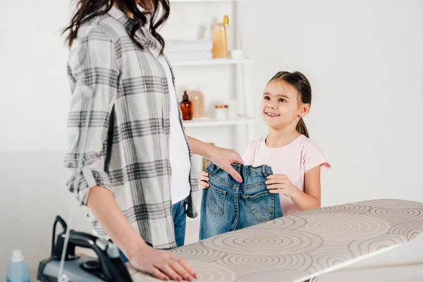 在家里烫衣板附近 母亲和女儿穿着牛仔裤的裁剪视图 — 图库照片