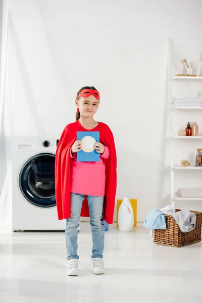 Child Standing Red Homemade Superhero Suit Holding Washing Powder Laundry — Stock Photo, Image