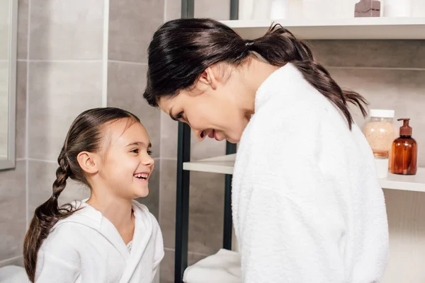 Mãe Olhando Para Filha Sorridente Roupão Banho Branco Perto Prateleiras — Fotografia de Stock