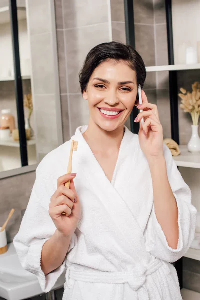 Woman Bathrobe Holding Toothbrush Talking Smartphone Bathroom — Stock Photo, Image