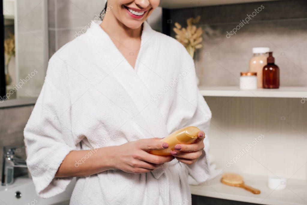 cropped view of woman holding bottle with shower gel in bathroom