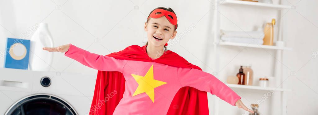 panoramic shot of child in red homemade suit with star sign having fun in laundry room