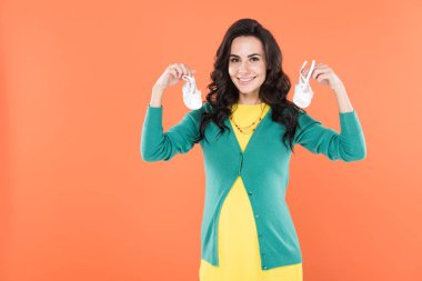 Bebek Patiği üzerinde turuncu izole tutan çekici esmer hamile kadın