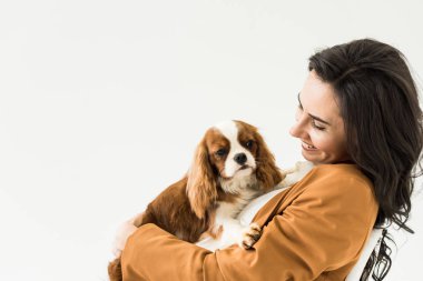 Excited brunette woman in brown jacket holding dog with smile isolated on white clipart