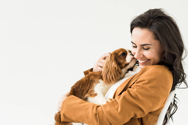 Happy laughing girl in brown jacket holding dog isolated on white
