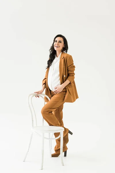 Lachende Schwangere Braunen Anzug Posiert Mit Stuhl Auf Weißem Hintergrund — Stockfoto