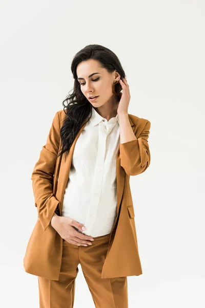 Zamyślony Brunetka Kobieta Ciąży Brązowym Garniturze Dotykając Brzuch Białym Tle — Zdjęcie stockowe