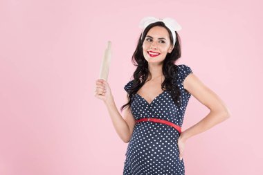 Attractive pregnant young woman holding rolling pin isolated on pink clipart