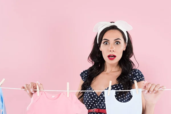 Shocked Brunette Woman Hanging Out Baby Clothes Clothesline Isolated Pink — Stock Photo, Image