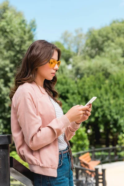 Atrakcyjna Dziewczyna Okulary Pomocą Smartphone Stojąc Parku — Zdjęcie stockowe