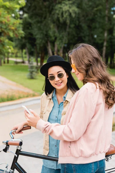 Fete Frumoase Ochelari Soare Zâmbind Timp Uită Smartphone Stând Lângă — Fotografie, imagine de stoc