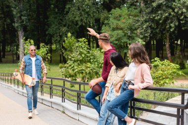longboard tutarak ve arkadaşları Park yakınındaki gülümseyen neşeli Afrikalı-Amerikalı adam