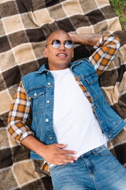 neşeli Afrikalı-Amerikalı gencin damalı battaniye var yalan güneş gözlüğü havai görünümü