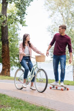 yakışıklı adam longboarding ve çekici kız binicilik bisiklet seyir 