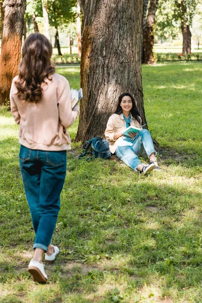 Lány Séta Könyvek Vidám Barátom Mosolyogva Miközben Park Közelében Hátulnézete — Stock Fotó