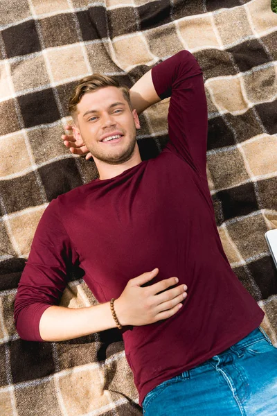 Overhead View Cheerful Young Man Smiling While Lying Checkered Blanket — Stock Photo, Image