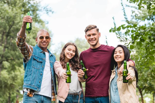 Feliz Grupo Multiétnico Amigos Sosteniendo Botellas Con Cerveza Mirando Cámara — Foto de Stock