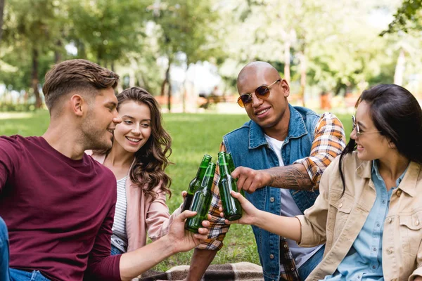 Χαρούμενα Πολυεθνική Ομάδα Φίλων Που Τσούγκριζαν Μπουκάλια Μπύρας Στο Πάρκο — Φωτογραφία Αρχείου