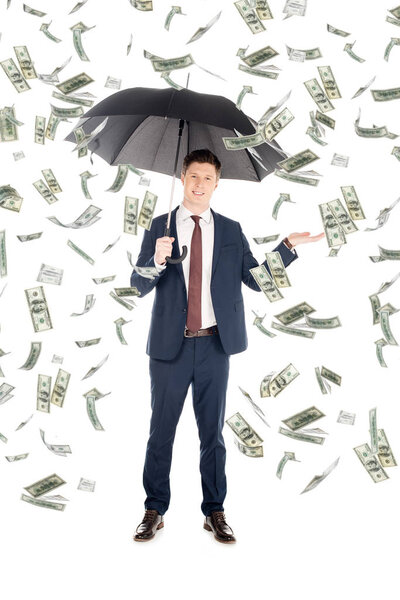 smiling businessman in suit with umbrella gesturing under money rain