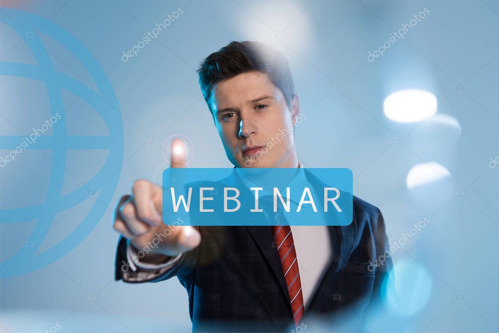 Confident businessman in suit pointing at webinar illustration in front on blue background