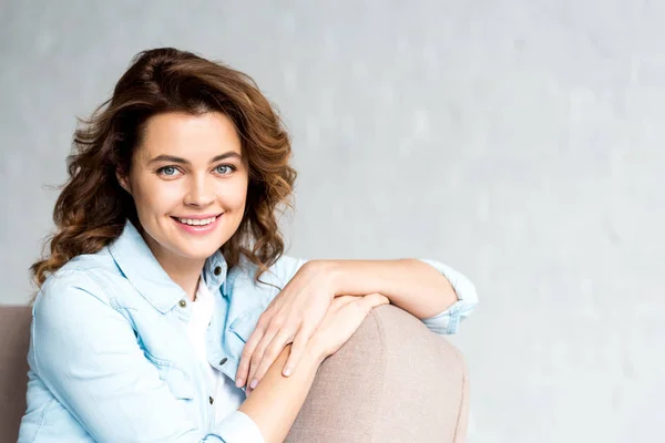 Hermosa Mujer Rizada Camisa Sentada Sofá Con Sonrisa Gris — Foto de Stock