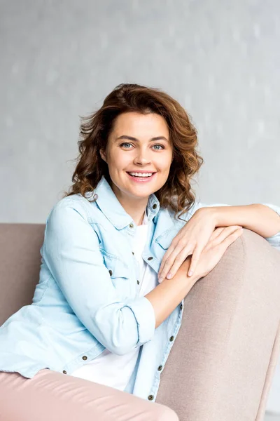 Cheerful Curly Woman Shirt Sitting Sofa Smiling Grey — Stock Photo, Image