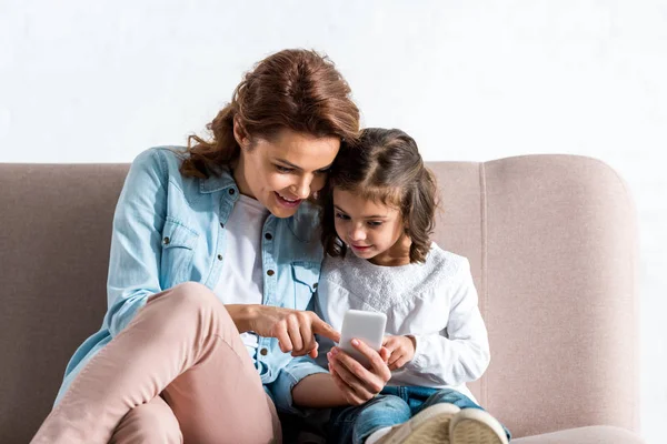 Äiti Tytär Istuvat Sohvalla Käyttävät Älypuhelinta Valkoisella — kuvapankkivalokuva